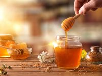 Hand With Dipper Picking Honey From A Jar Of Honey